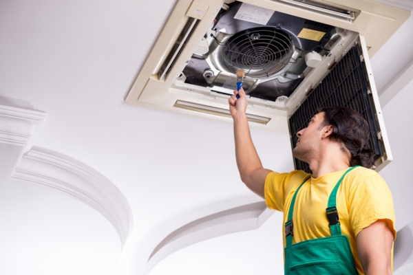 HVAC technician inspecting indoor air conditioner unit