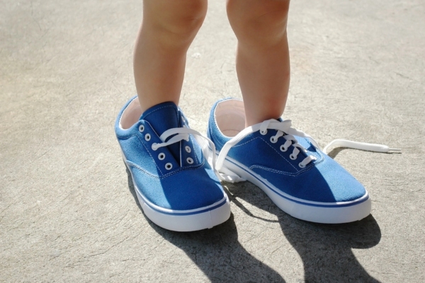 image of a cropped baby's legs and feet wearing adult shoes depicting incorrect heat pump size