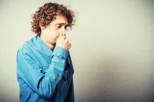 man covering his nose depicting furnace heating oil smell